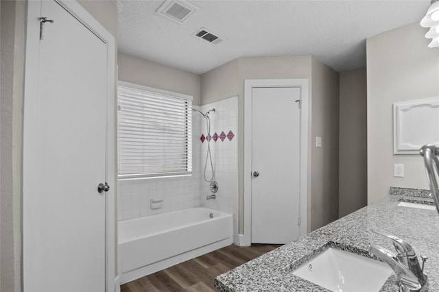 full bath featuring visible vents, a sink, a textured ceiling, and wood finished floors