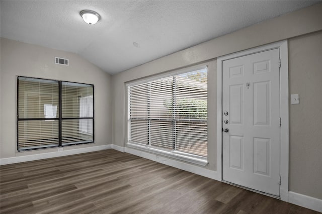 entrance foyer featuring a textured ceiling, wood finished floors, visible vents, baseboards, and vaulted ceiling