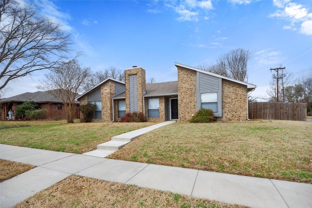 mid-century modern home with a front lawn, a chimney, fence, and brick siding