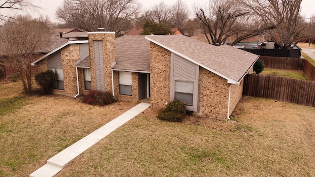 view of front of property featuring brick siding, a chimney, a front yard, and fence