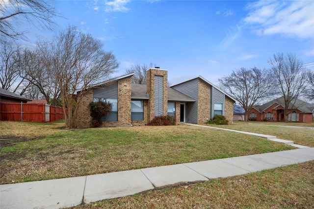 mid-century home featuring a front yard, brick siding, fence, and a chimney