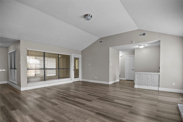 unfurnished living room with a textured ceiling, wood finished floors, visible vents, baseboards, and vaulted ceiling