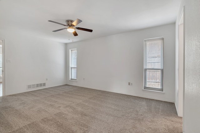 spare room featuring ceiling fan, carpet floors, and visible vents