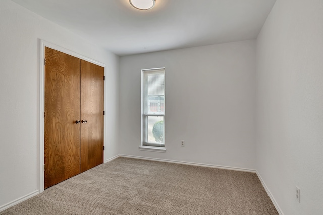 unfurnished bedroom with carpet floors, a closet, and baseboards