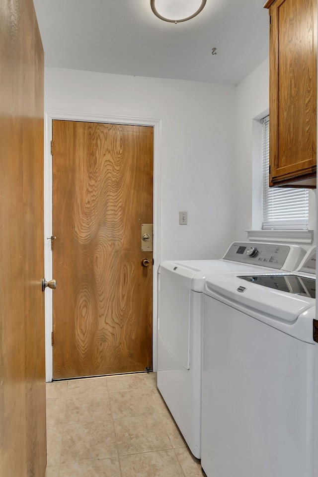 washroom with cabinet space, light tile patterned floors, and washing machine and clothes dryer