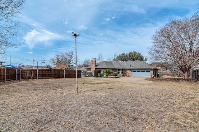 view of yard featuring an attached garage and fence