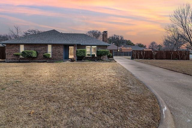 single story home featuring brick siding, a shingled roof, a lawn, a gate, and fence