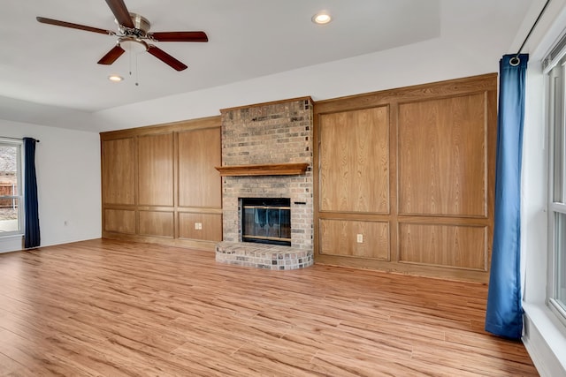 unfurnished living room with light wood-style floors, recessed lighting, a fireplace, and a ceiling fan