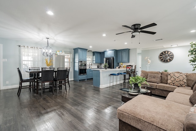 living room featuring ceiling fan with notable chandelier, dark wood-type flooring, visible vents, and recessed lighting