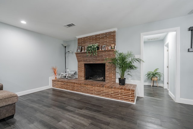 living area featuring a brick fireplace, wood finished floors, visible vents, and baseboards