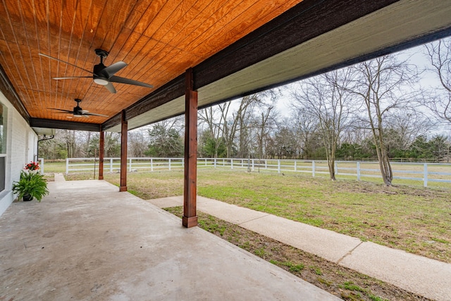 view of patio with a ceiling fan, a rural view, and fence