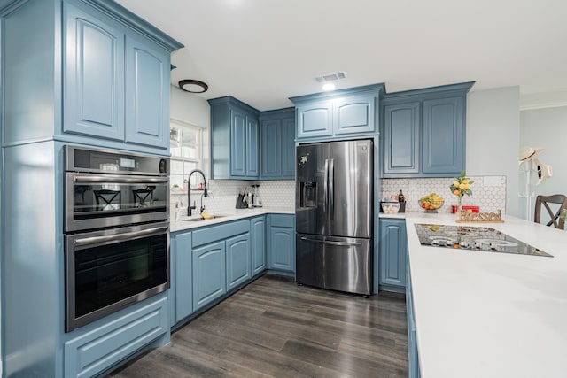 kitchen featuring stainless steel appliances, light countertops, visible vents, a sink, and blue cabinets