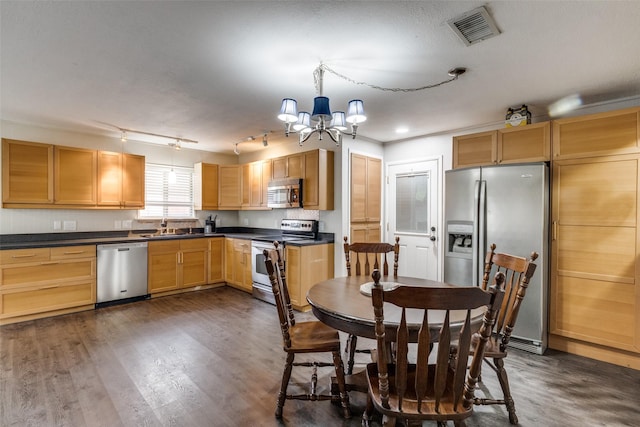 kitchen featuring appliances with stainless steel finishes, dark countertops, visible vents, and a sink