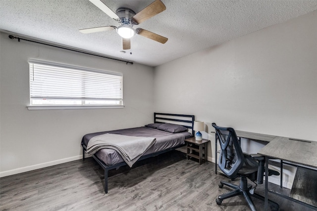 bedroom with a ceiling fan, a textured ceiling, baseboards, and wood finished floors