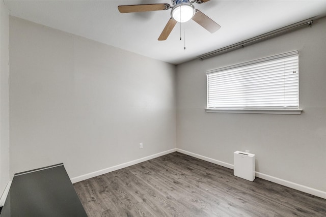 unfurnished room featuring a ceiling fan, baseboards, and wood finished floors