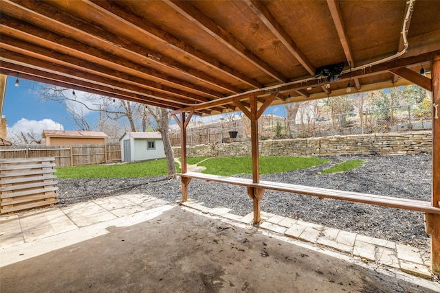 view of patio featuring a shed, a fenced backyard, and an outbuilding