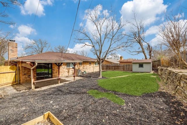 rear view of house with a yard, brick siding, an outdoor structure, and a fenced backyard