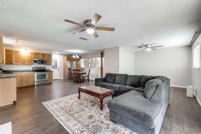 living room with baseboards, visible vents, dark wood-style flooring, and ceiling fan with notable chandelier