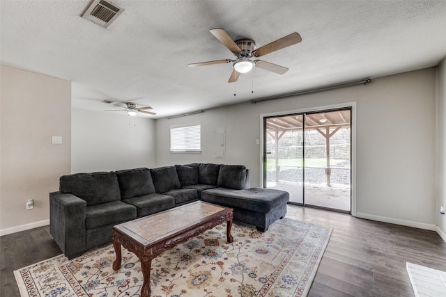 living area featuring a textured ceiling, wood finished floors, visible vents, and baseboards