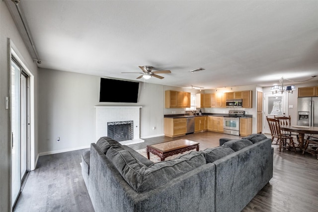 living area featuring a fireplace with raised hearth, dark wood-type flooring, visible vents, and baseboards