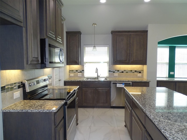 kitchen featuring stone countertops, a sink, marble finish floor, dark brown cabinets, and appliances with stainless steel finishes