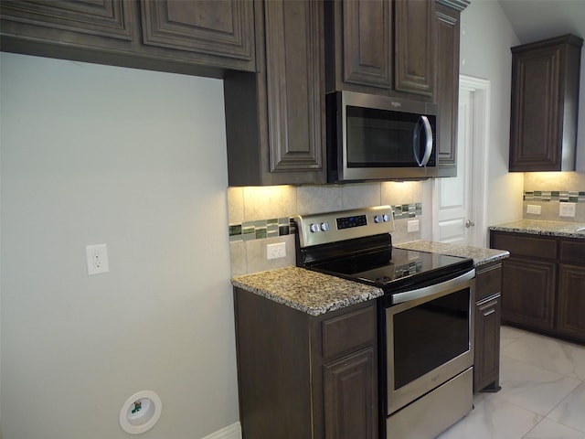 kitchen with stainless steel appliances, decorative backsplash, light stone counters, and dark brown cabinets