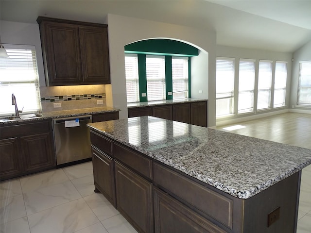 kitchen featuring stone counters, dishwasher, backsplash, and a sink