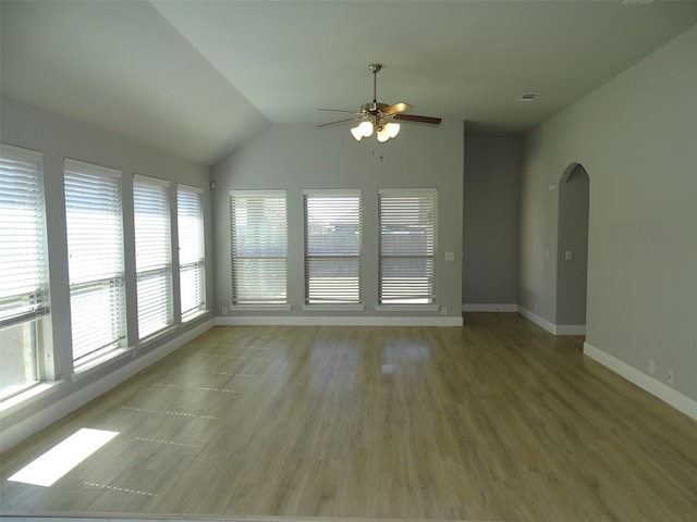 interior space featuring baseboards, arched walkways, lofted ceiling, ceiling fan, and wood finished floors