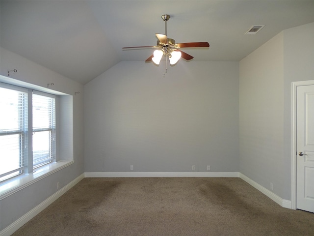 carpeted spare room featuring lofted ceiling, ceiling fan, visible vents, and baseboards