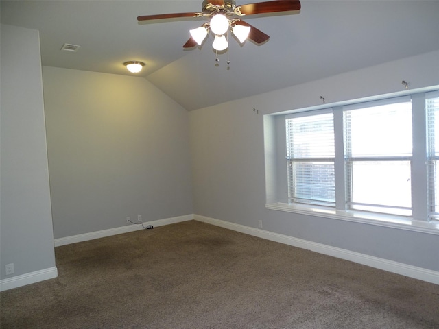 carpeted spare room with lofted ceiling, a ceiling fan, visible vents, and baseboards