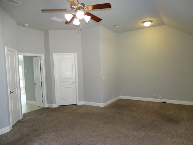 carpeted empty room with lofted ceiling, baseboards, visible vents, and a ceiling fan