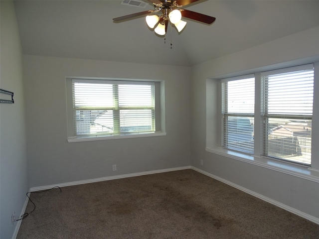 carpeted empty room featuring lofted ceiling, visible vents, a ceiling fan, and baseboards