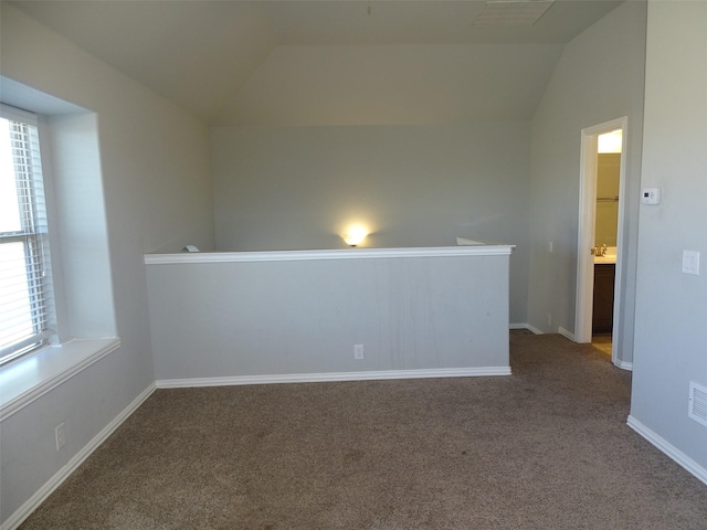 unfurnished room featuring lofted ceiling, carpet flooring, visible vents, and baseboards