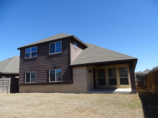 back of house featuring brick siding, a patio, a shingled roof, a lawn, and a fenced backyard