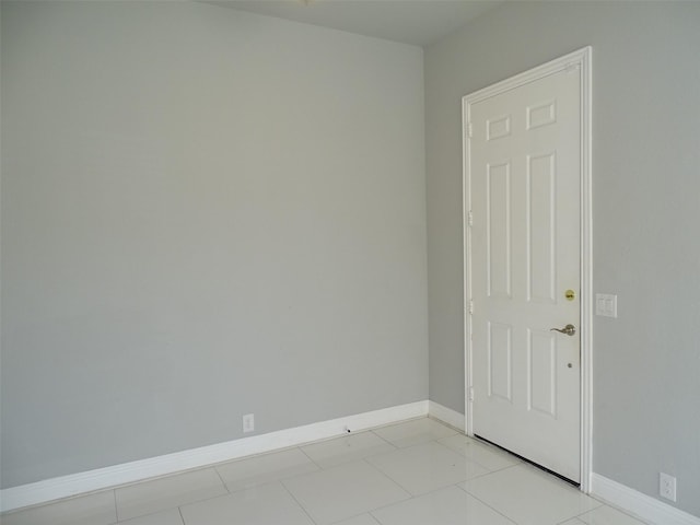 spare room featuring light tile patterned flooring and baseboards