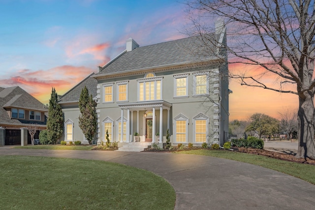 colonial-style house with a chimney, a front lawn, and stucco siding