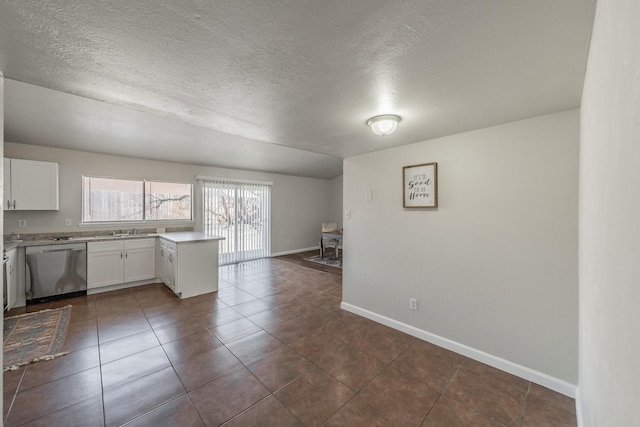 kitchen with baseboards, dishwasher, light countertops, white cabinets, and a sink