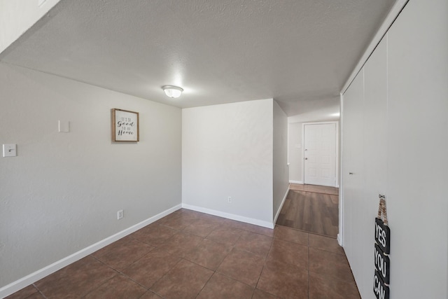 spare room with dark tile patterned flooring, baseboards, and a textured ceiling