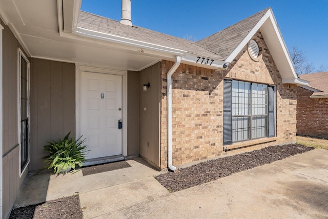 property entrance with brick siding and a shingled roof