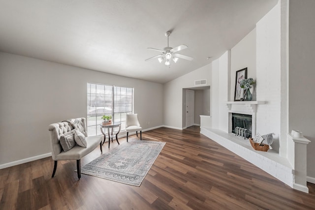 sitting room with visible vents, wood finished floors, baseboards, a fireplace, and lofted ceiling