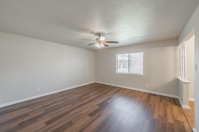 spare room with baseboards, dark wood finished floors, and a ceiling fan