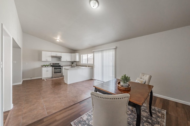 dining area featuring baseboards, lofted ceiling, and wood finished floors