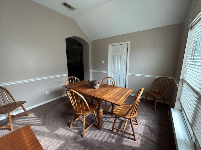 carpeted dining space featuring visible vents, arched walkways, a baseboard radiator, baseboards, and vaulted ceiling