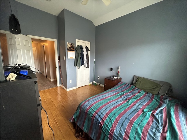 bedroom with lofted ceiling, wood finished floors, baseboards, and ceiling fan