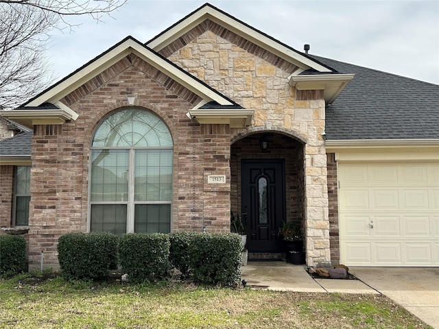 doorway to property with a garage, stone siding, brick siding, and a shingled roof