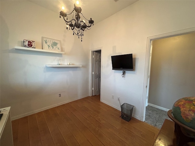 unfurnished living room with a chandelier, baseboards, and hardwood / wood-style flooring