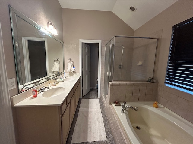 bathroom featuring a garden tub, a sink, a shower stall, double vanity, and lofted ceiling