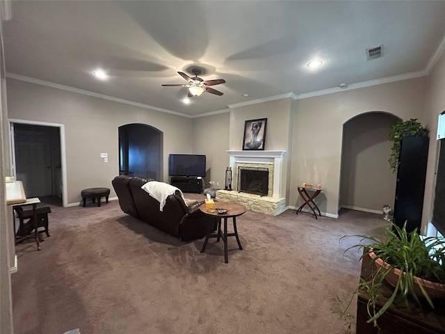 carpeted living area featuring baseboards, arched walkways, ceiling fan, and a fireplace