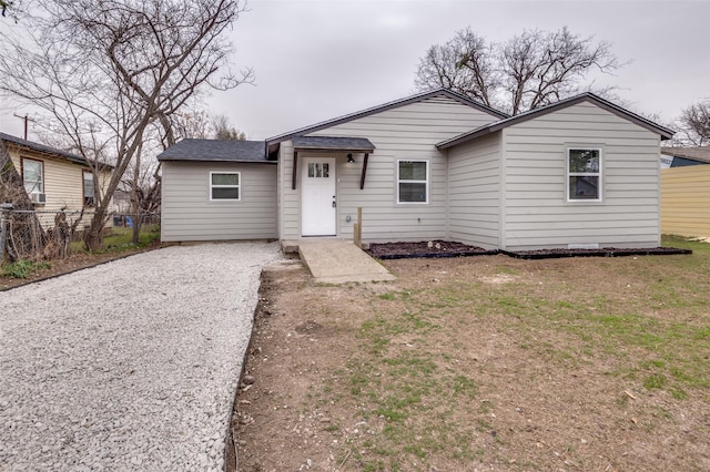 view of front of house with a shingled roof, a front yard, fence, and driveway