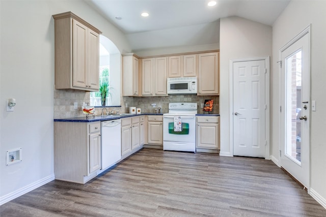 kitchen featuring light wood-type flooring, backsplash, dark countertops, white appliances, and vaulted ceiling